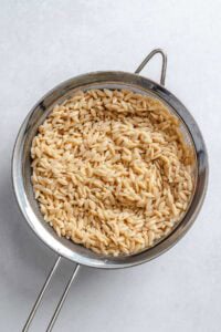Process shot showing orzo in a strainer.