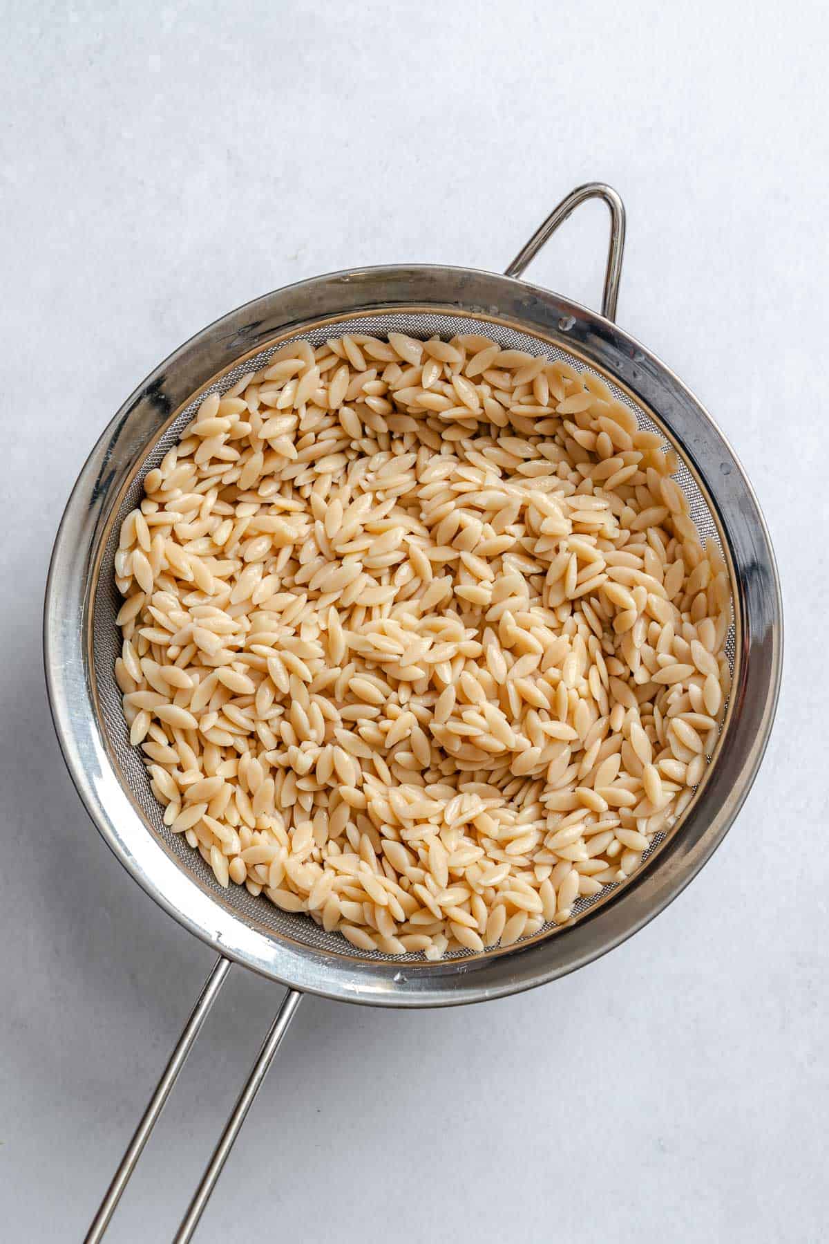 Process shot showing orzo in a strainer.