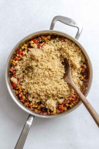 Process shot showing adding quinoa to pot.