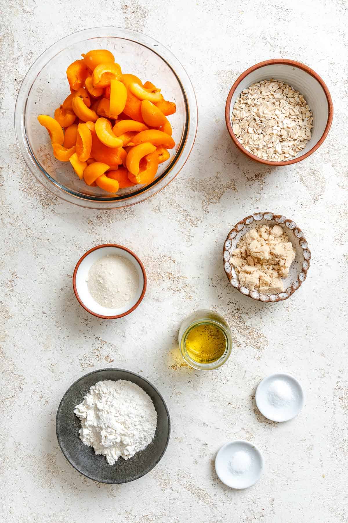 Ingredients for Easy Apricot Crumble (With Oats) measured out on a white surface.