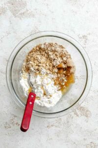 Process shot showing apricots and ingredients being mixed together in a bowl.