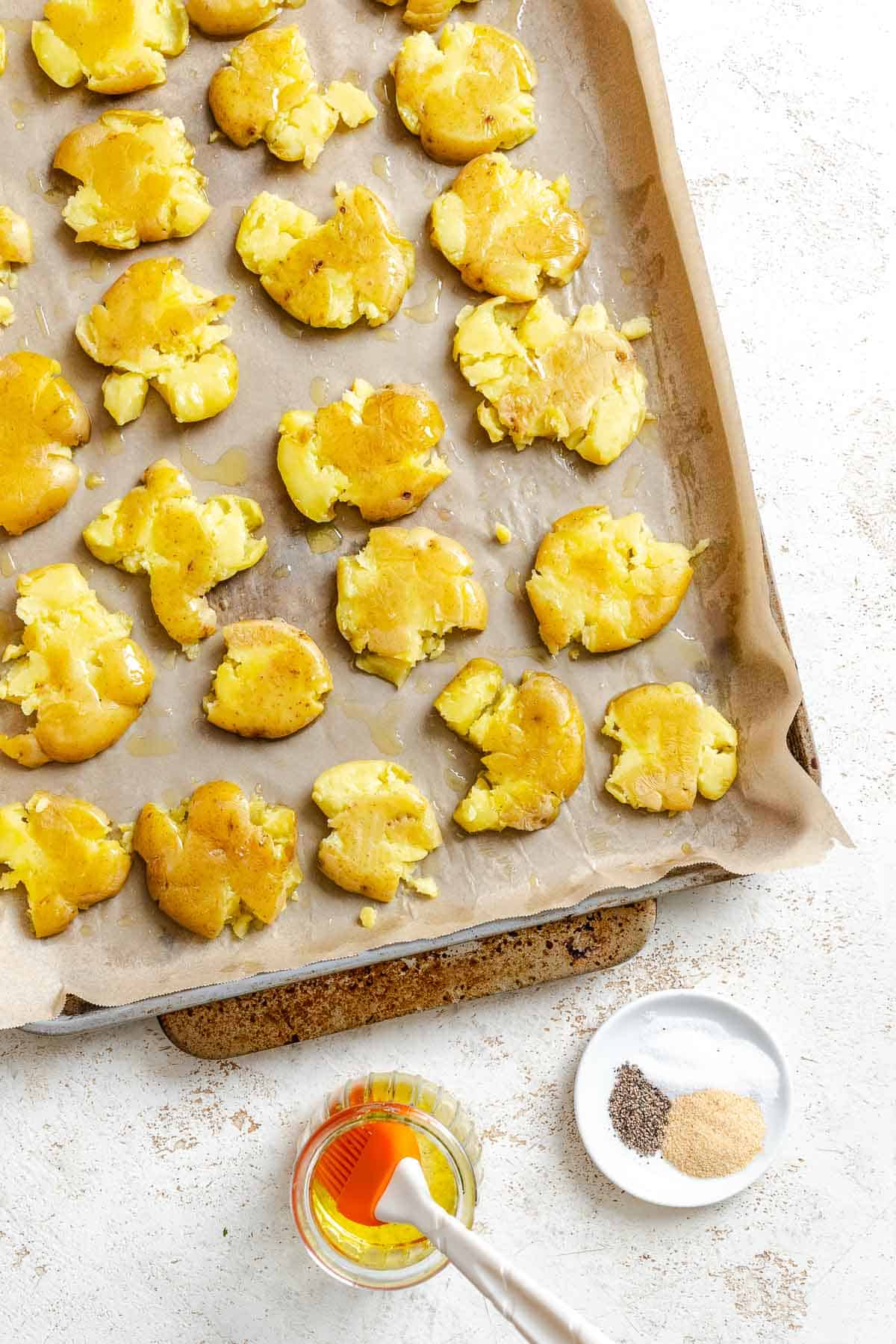 Process shot showing post smashed potatoes on baking dish.