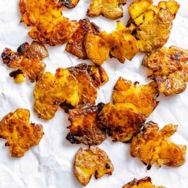 Completed Crispy Smashed Potatoes on a white surface.