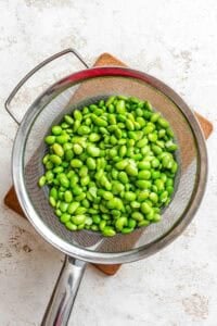 Process shot showing edamame in a strainer.