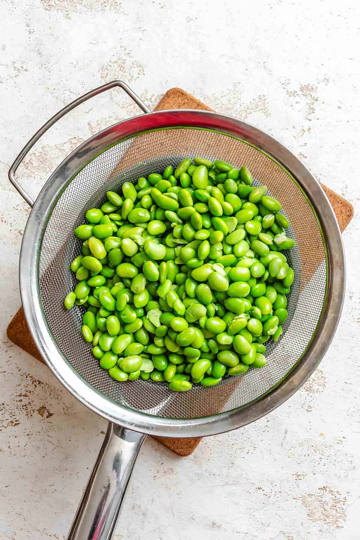Process shot showing edamame in a strainer.