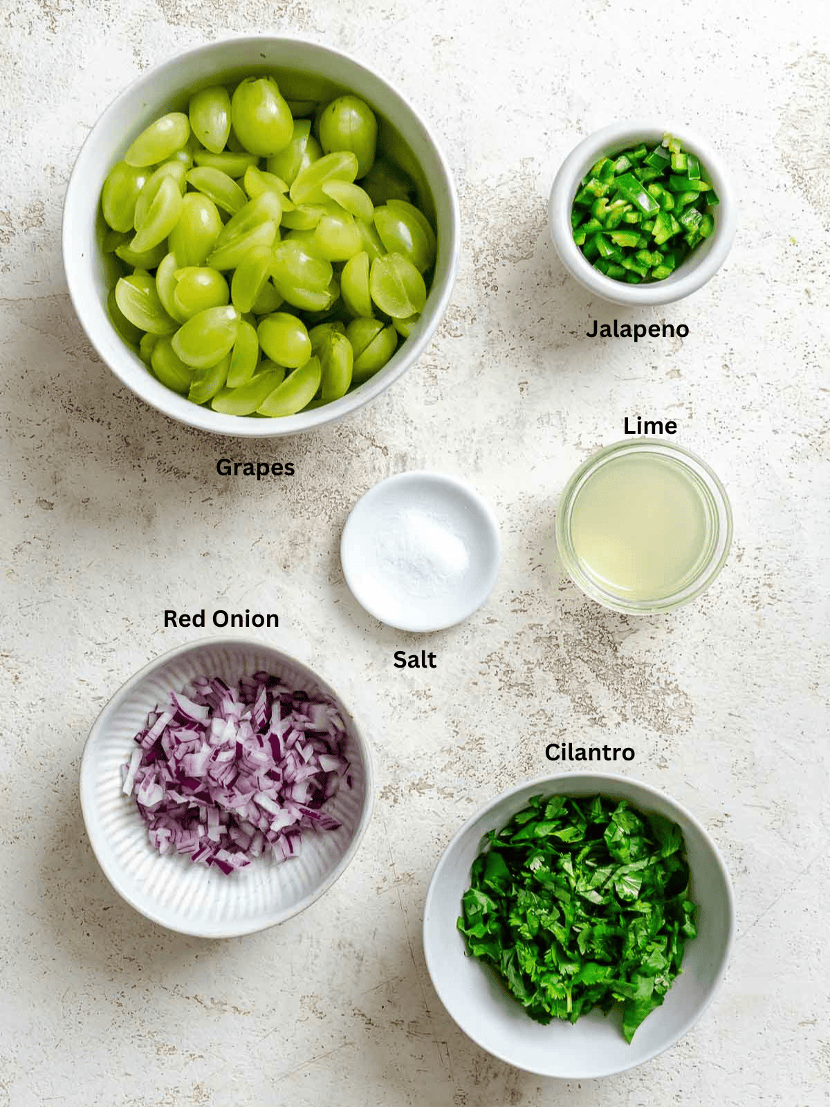 Ingredients for Fresh Grape Salsa measured out on a white surface. 