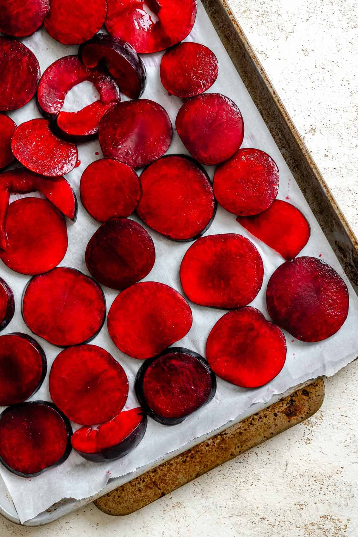 Process shot showing plums on baking sheet.