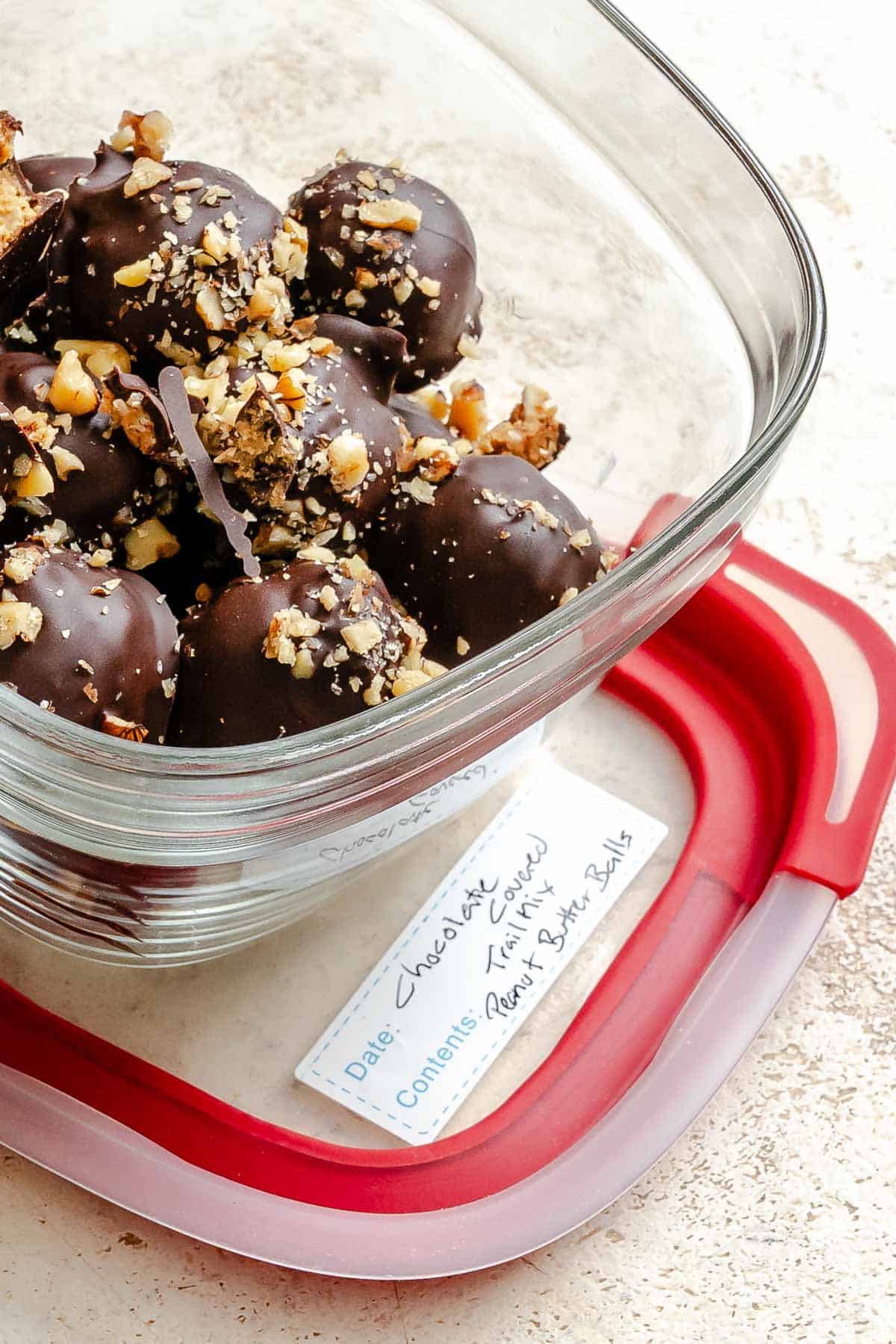 Completed Chocolate Covered Peanut Butter Balls (+ Add-Ins) in a storage container.