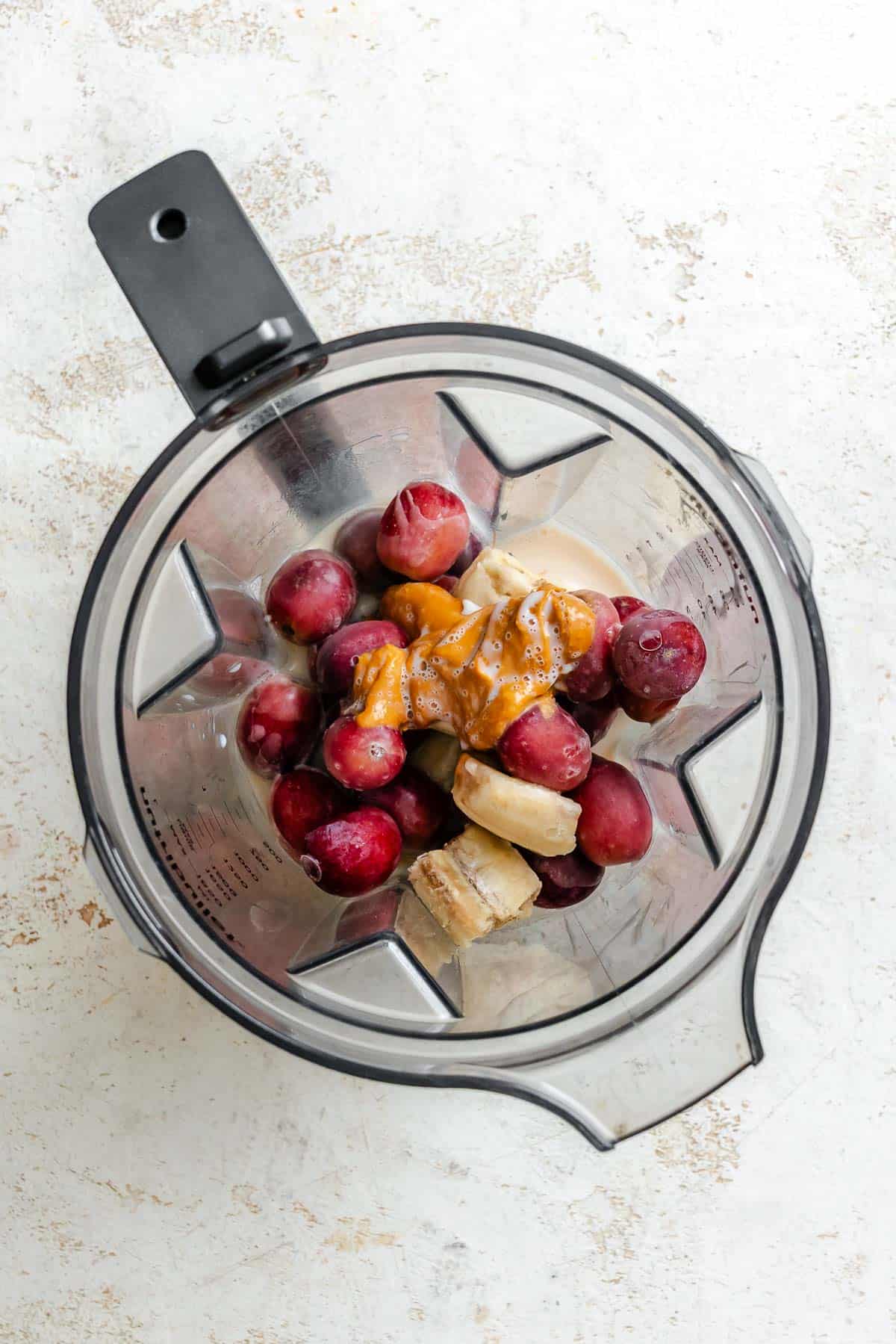 Process shot showing Easy Grape Smoothie ingredients in blender.