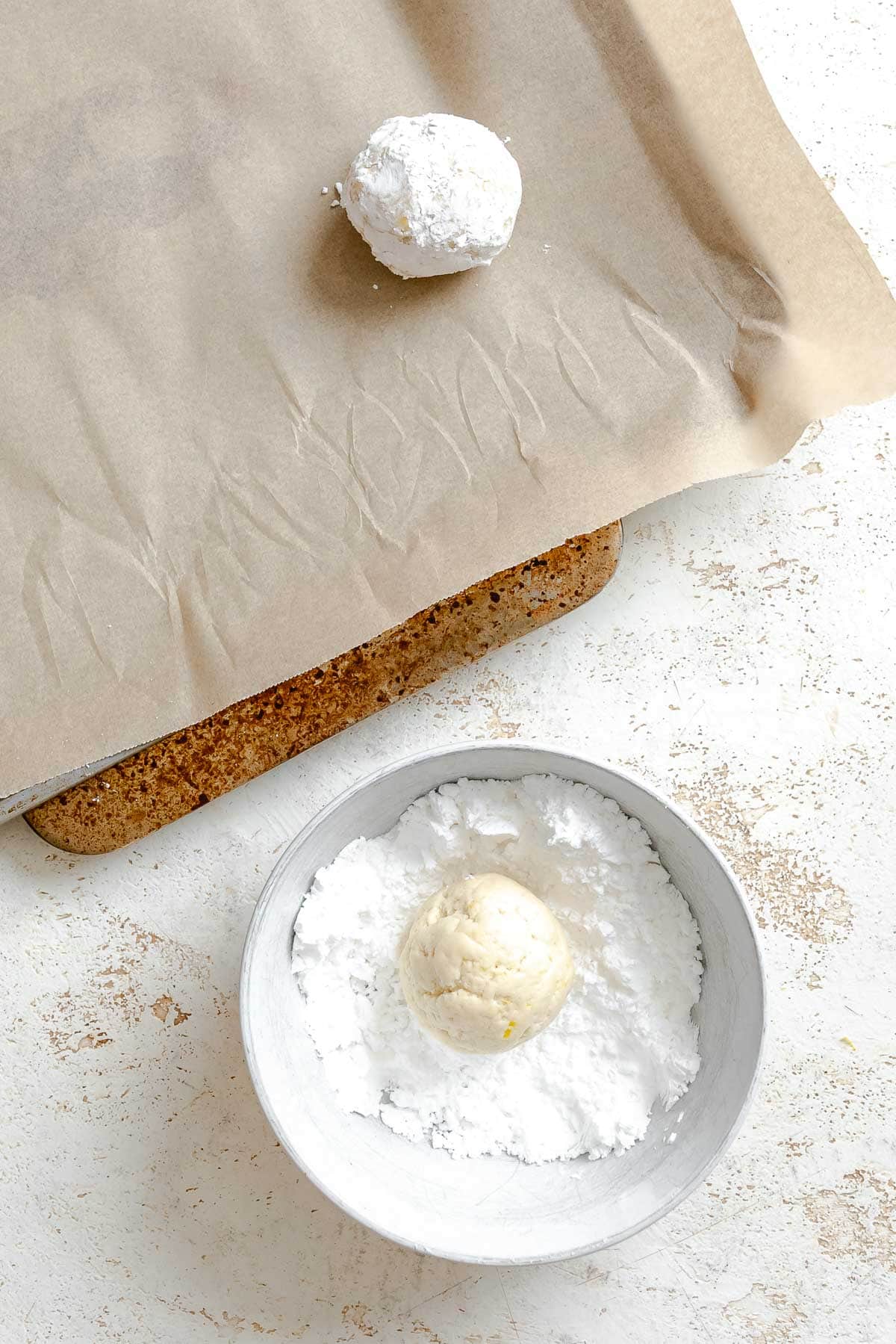 Process shot showing dipping dough into powdered sugar.