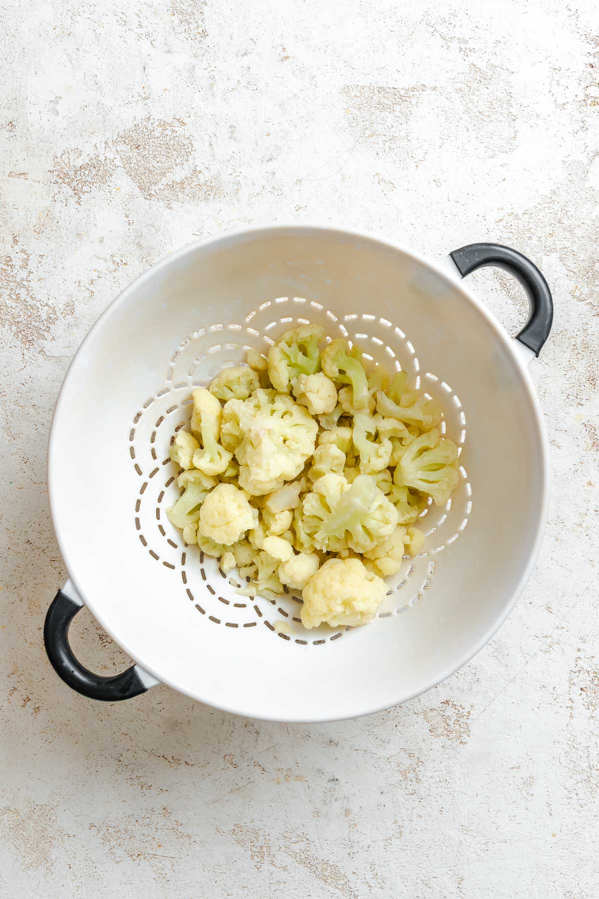 Process shot showing straining cauliflower in strainer.