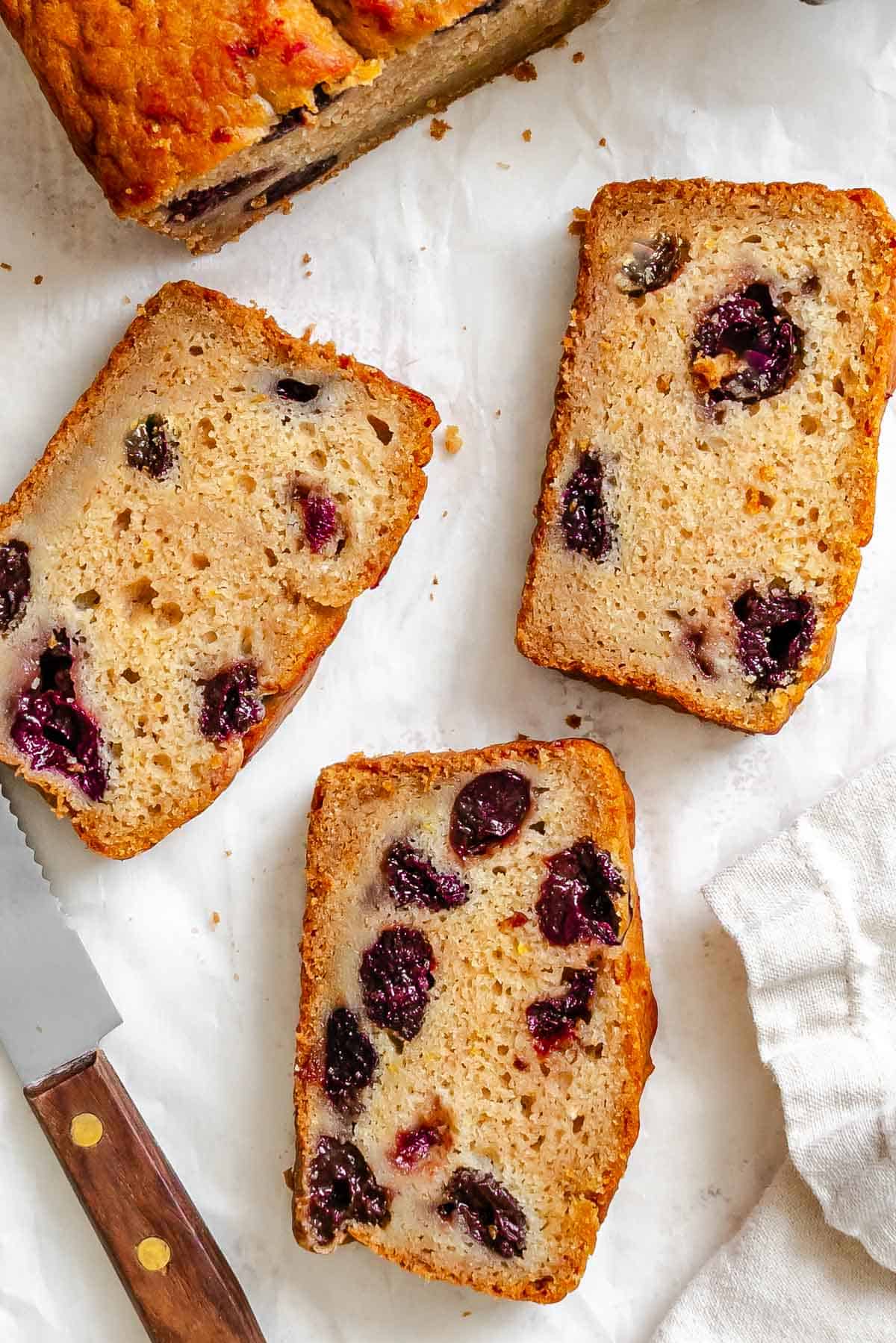Completed slices of Cranberry Orange Bread (Eggless!) on a white surface.