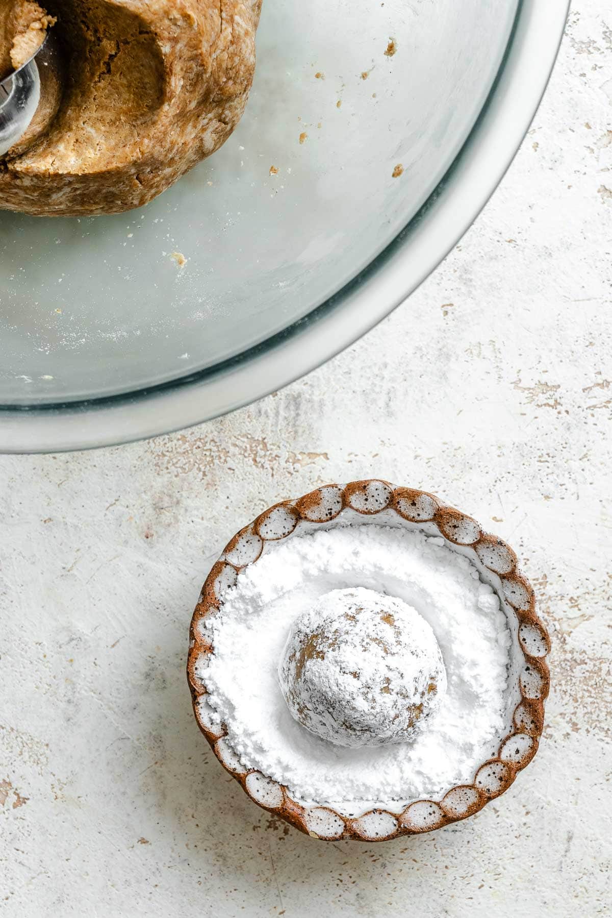 Process shot showing placing cookie dough in sugar.