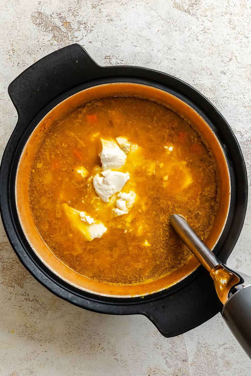 Process shot showing using immersion blender in pot.