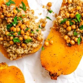 Roasted butternut squash halves topped with quinoa, chickpeas, and chopped parsley.