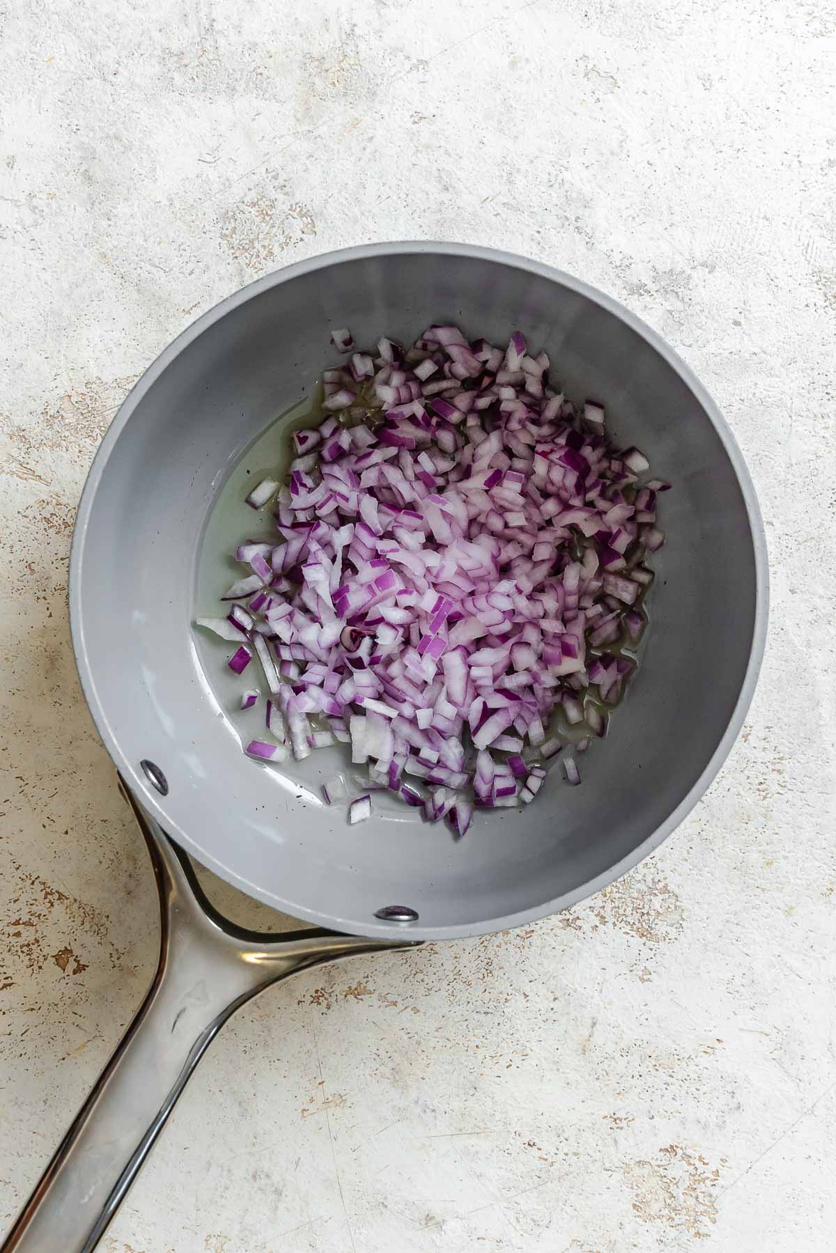 Process shot showing onions cooking in pan.