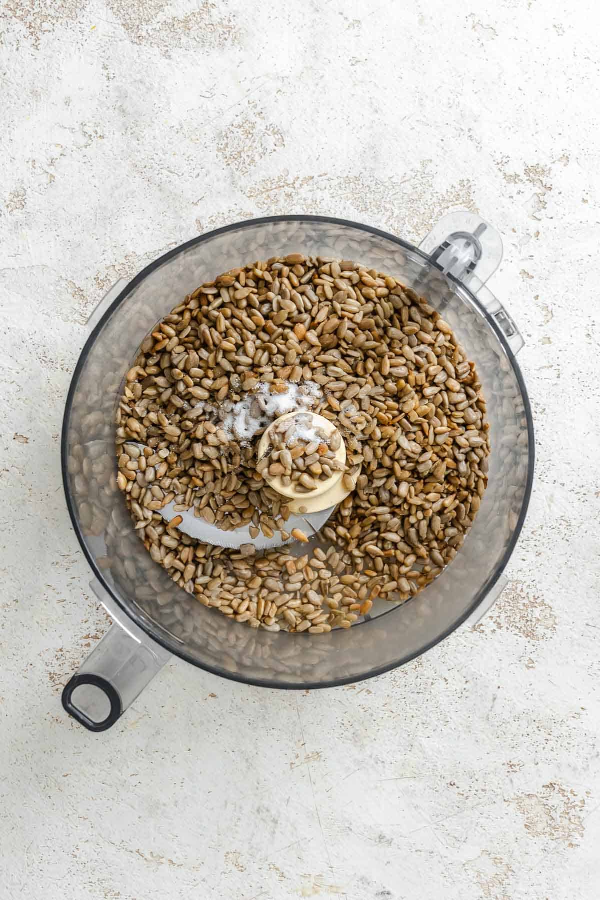 Process shot showing sunflower seeds mixing in food processor.