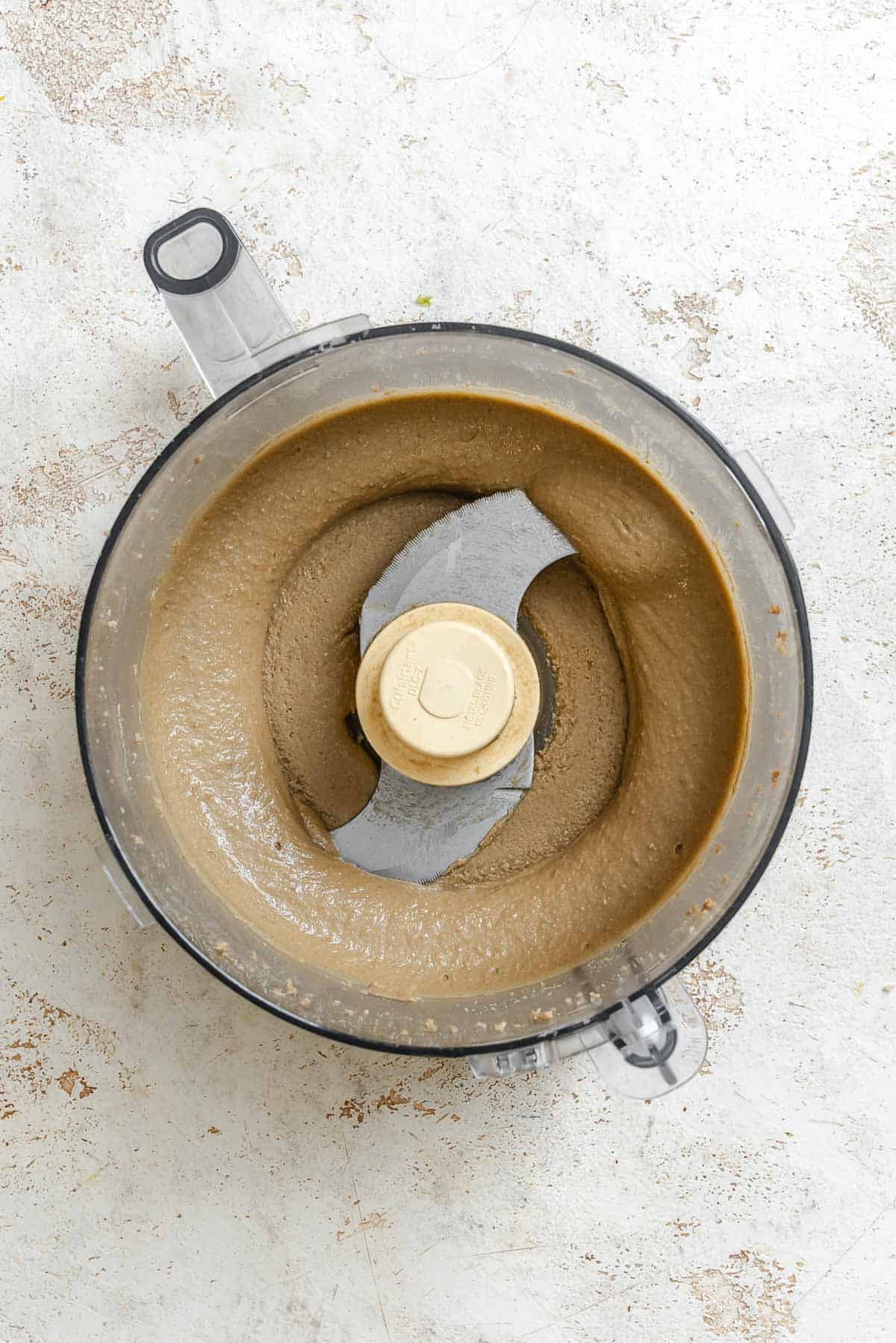 Process shot showing sunflower seeds mixing in food processor.