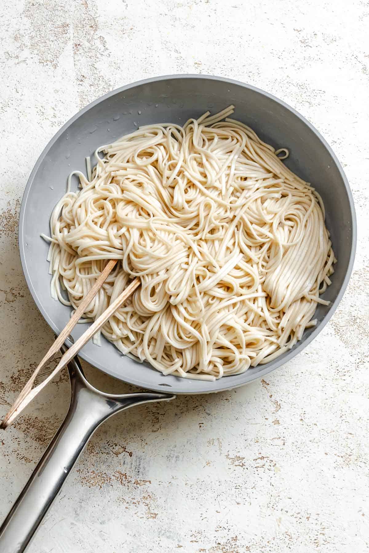 Process shot showing cooking noodles in a pan.