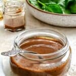 Completed Spinach Salad Dressing in a jar on a white surface.