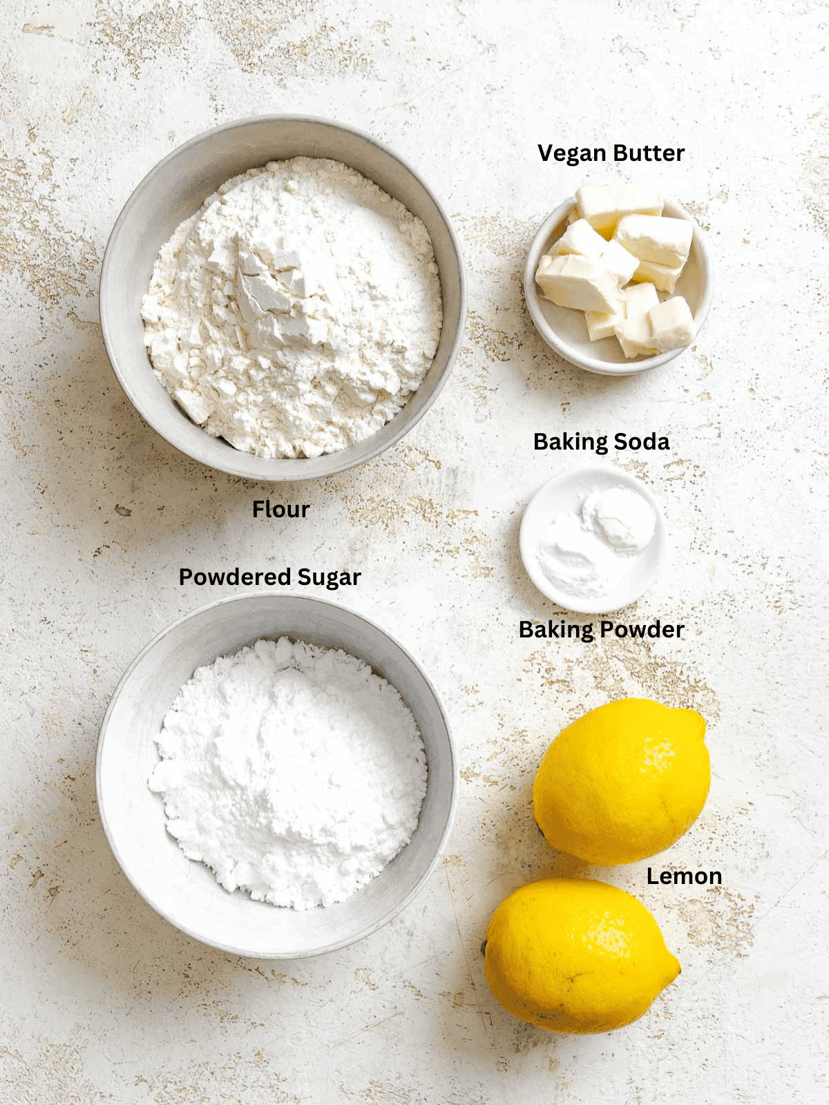 Ingredients for Lemon Crinkle Cookies measured out on a white surface.