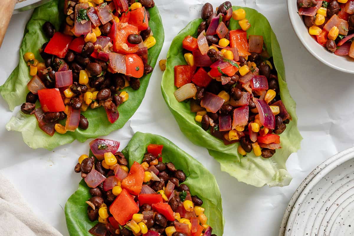 Several completed Vegetarian Lettuce Wraps (Beans & Corn) on a white surface.