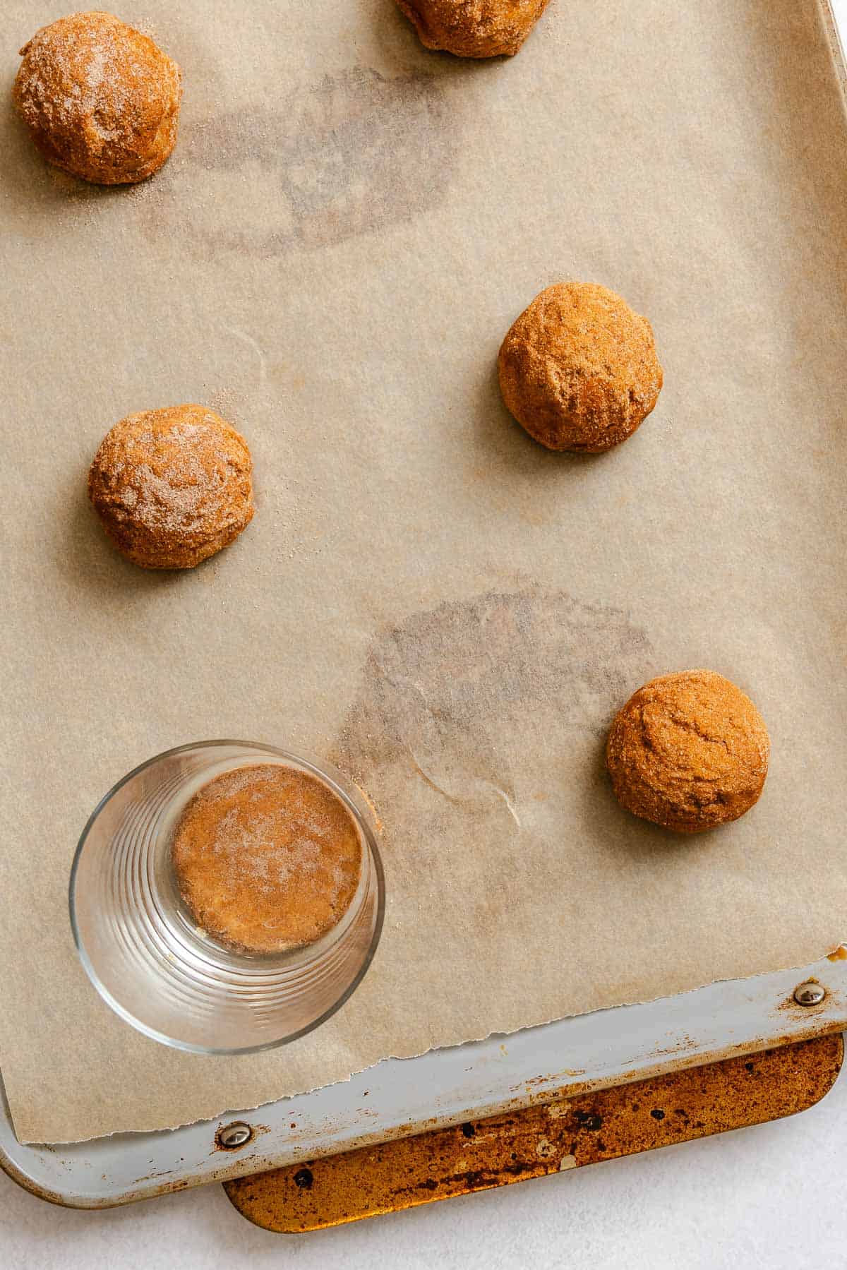 Process shot showing flattening cookies with a glass.