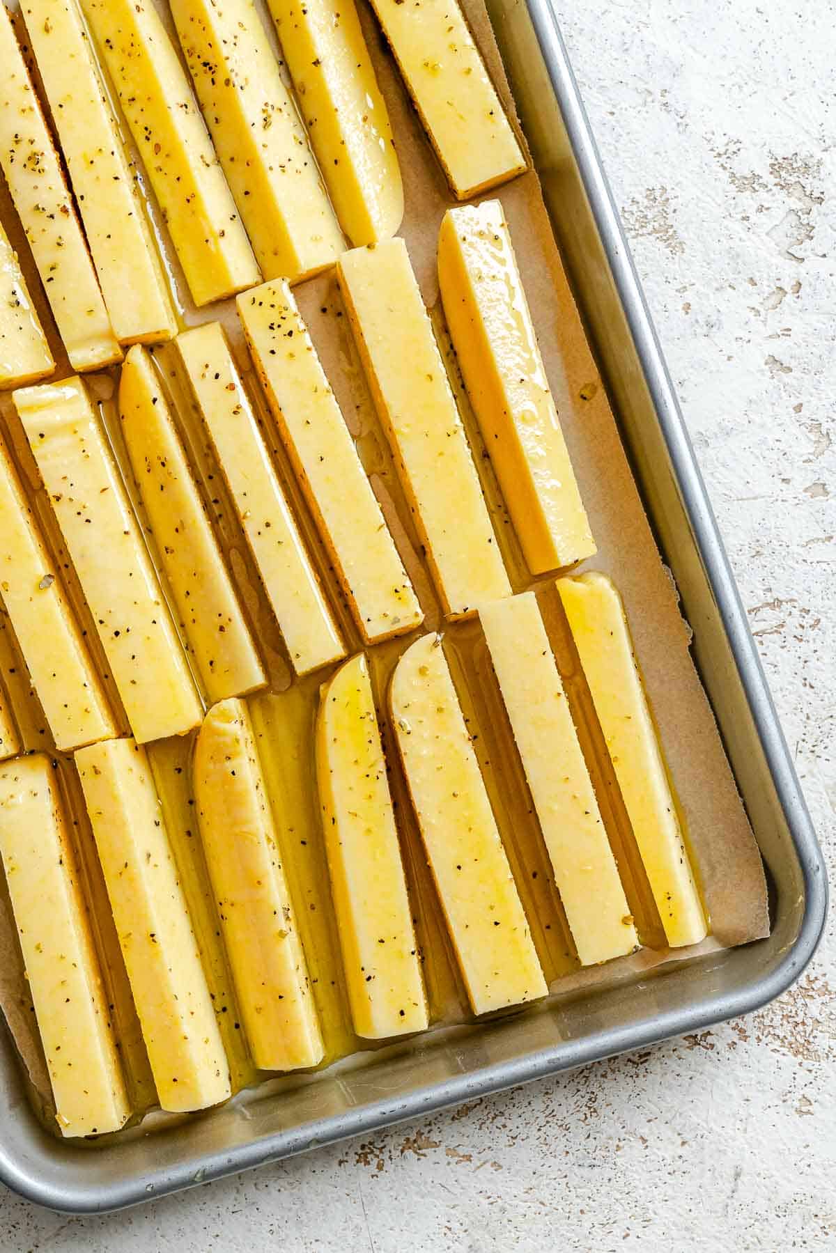 Process shot showing polenta fries added to baking tray.