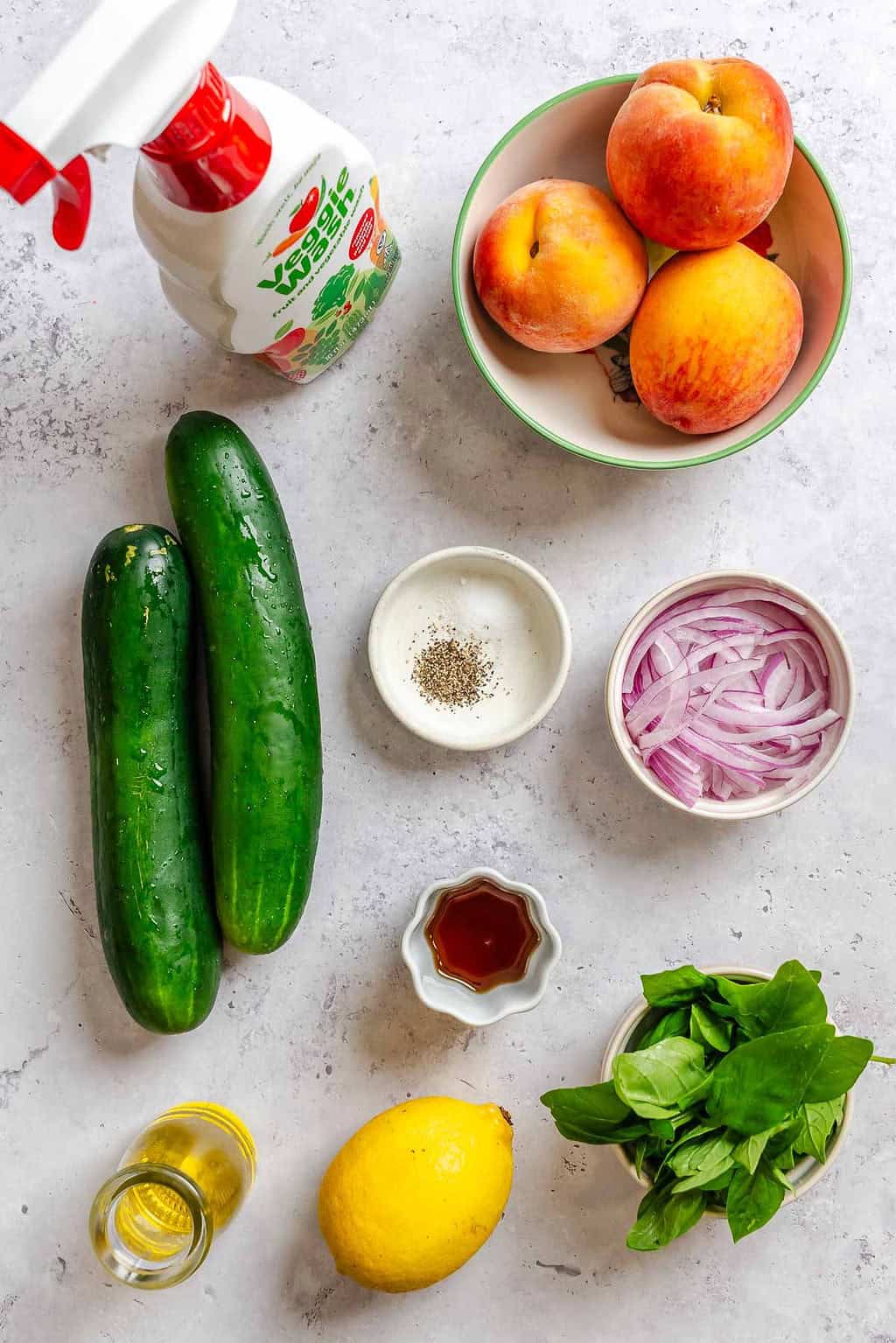 Ingredients for Cucumber Peach Salad measured out on a white surface.
