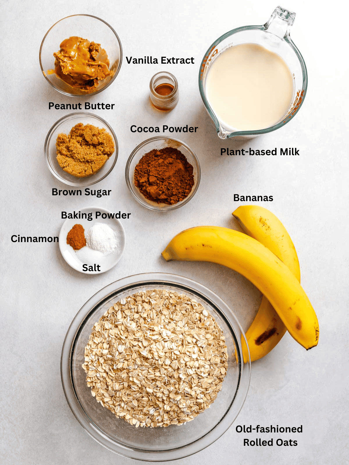 Ingredients for Chocolate Banana Baked Oatmeal (with peanut butter) measured out on a white surface.