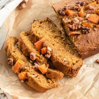 Slices of vegan pumpkin bread fanned out next to the loaf.