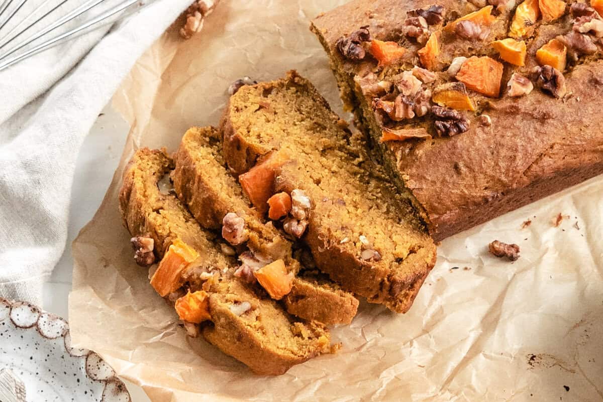 Slices of vegan pumpkin bread fanned out next to the loaf.