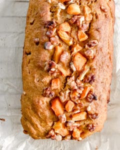 Baked vegan pumpkin bread loaf topped with walnuts, seen from above.